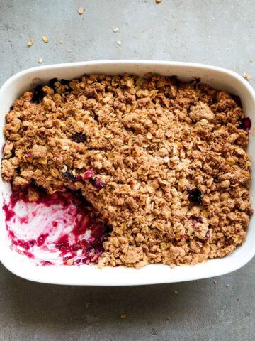 A close up of a crisp with apple and blieberries.