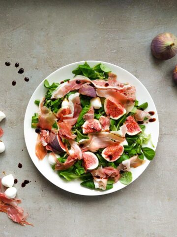 A salad with figs on a white plate.