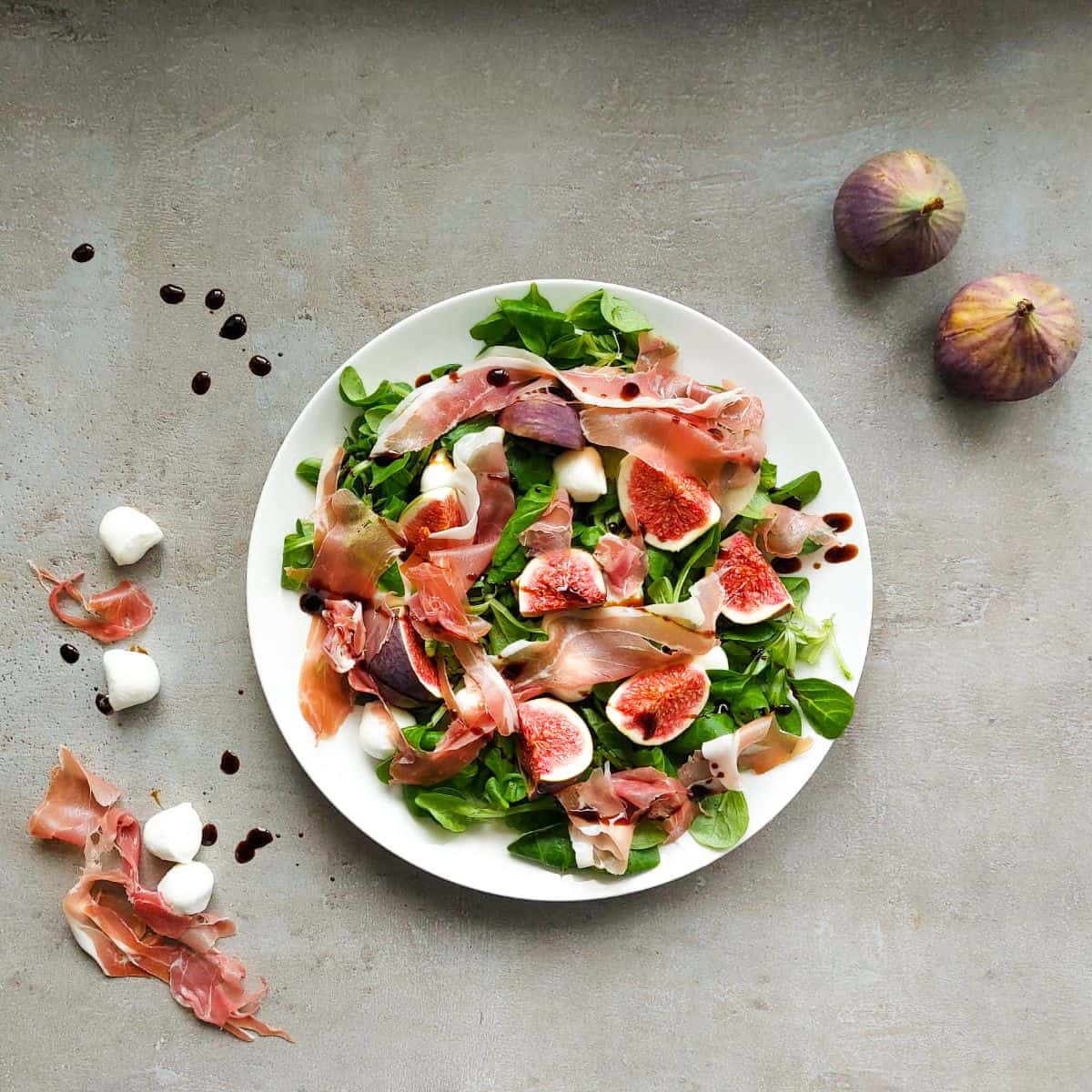 A salad with figs on a white plate.