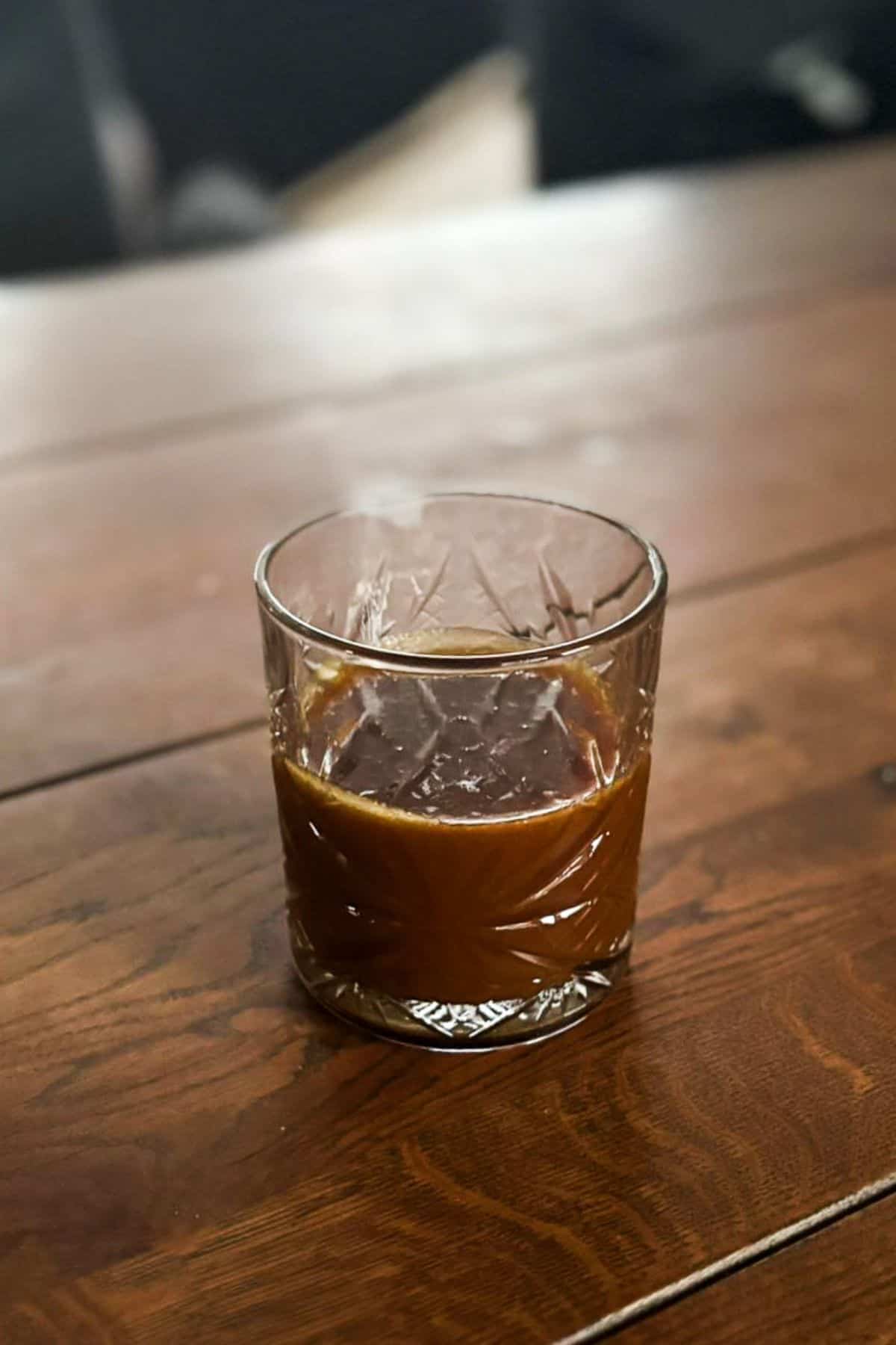 Homemade dark caramel sauce in a glass.